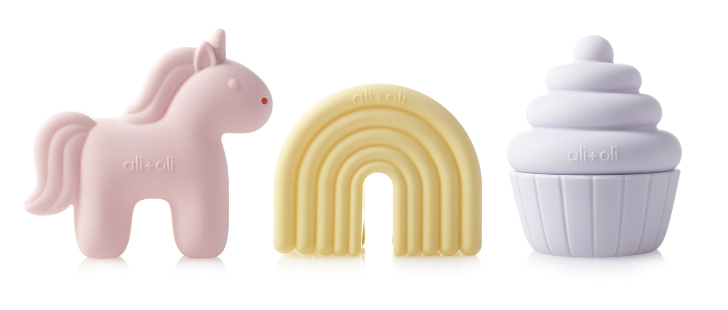 Three silicone teethers shaped like a unicorn, rainbow, and cupcake on a white background.