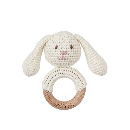 Crocheted bunny rattle with wooden ring on a white background