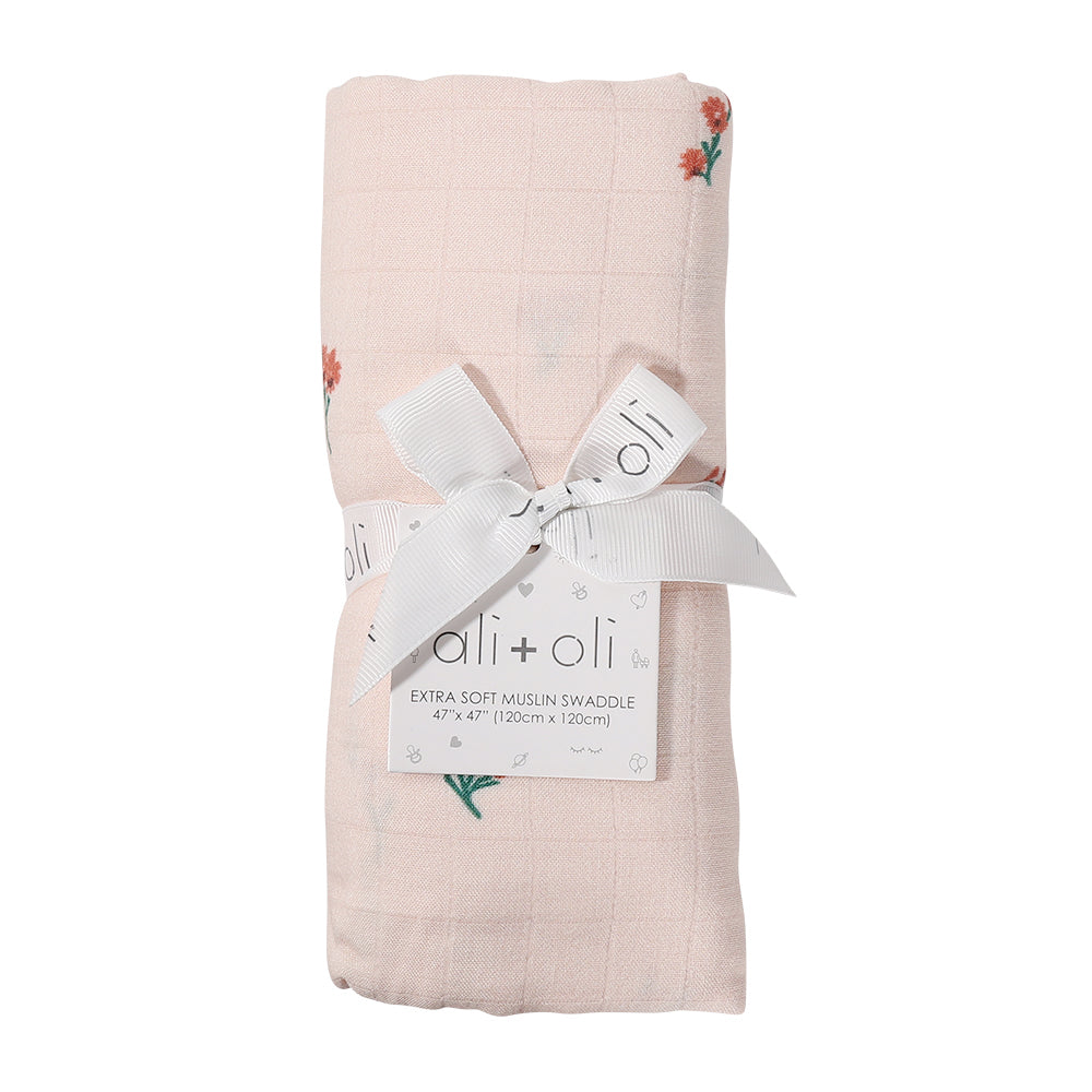 Folded pink swaddle blanket with floral embroidery and 'oli+oli' label on a white background