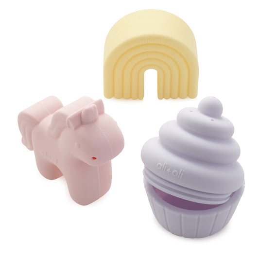 Pink Unicorn-shaped object, yellow rainbow-shaped object, and purple cupcake-shaped object on a white background